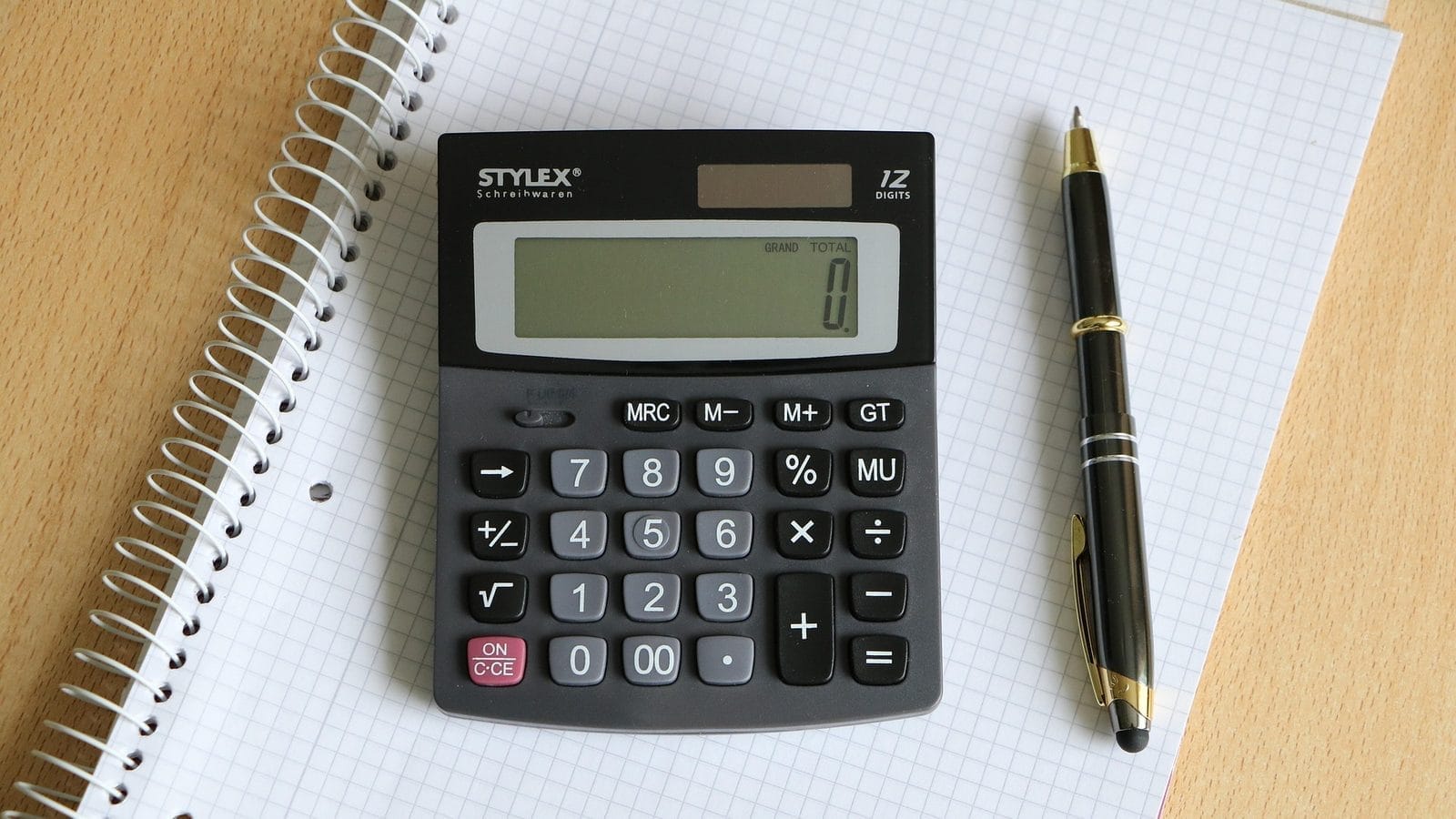 A calculator and pen on a notepad, working out accountancy costs