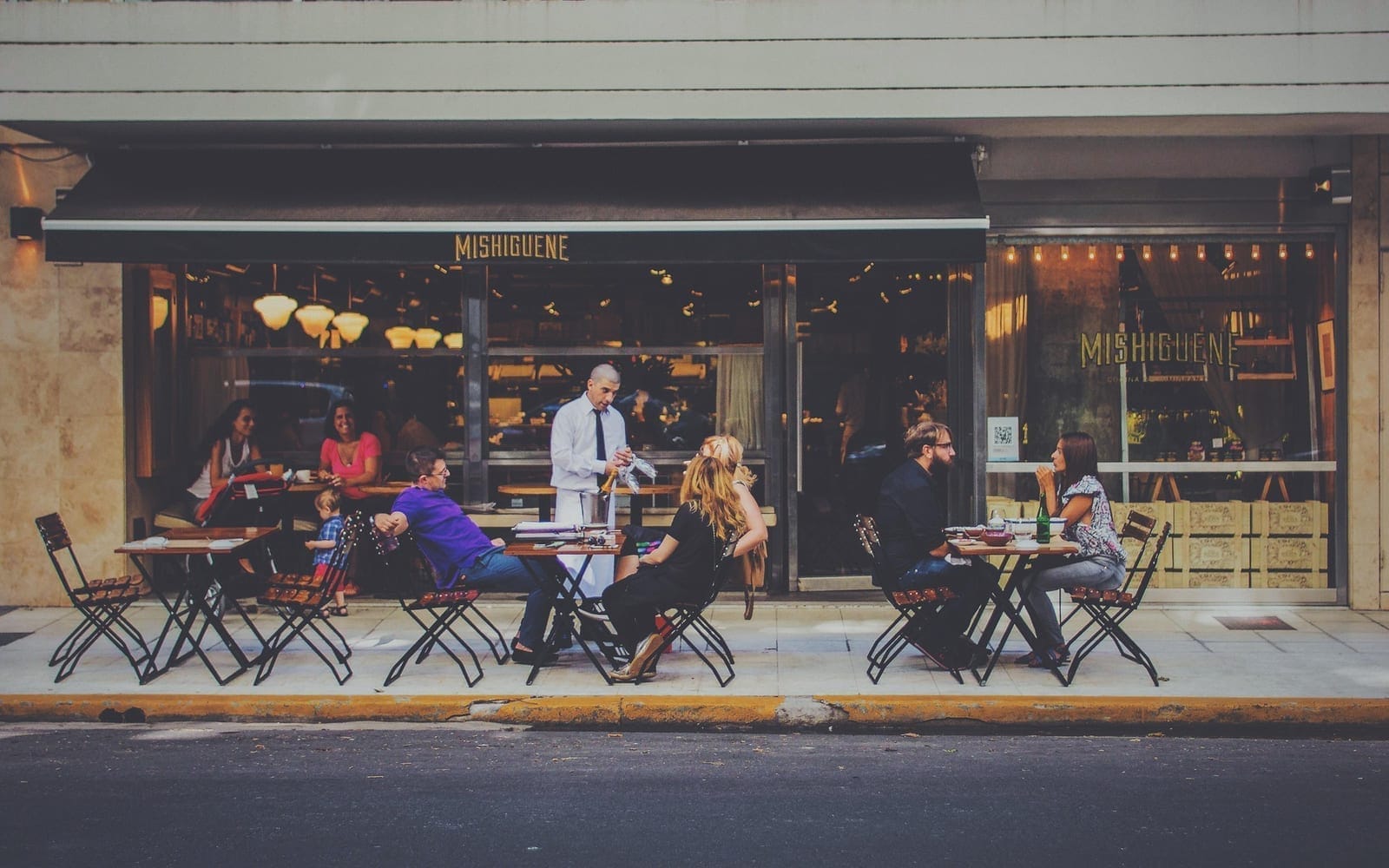 Diners at the outdoor pavement tables of a restaurant